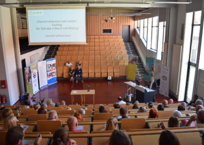 Hörsaal UNI von oben. Gäste hören Referenten zu.